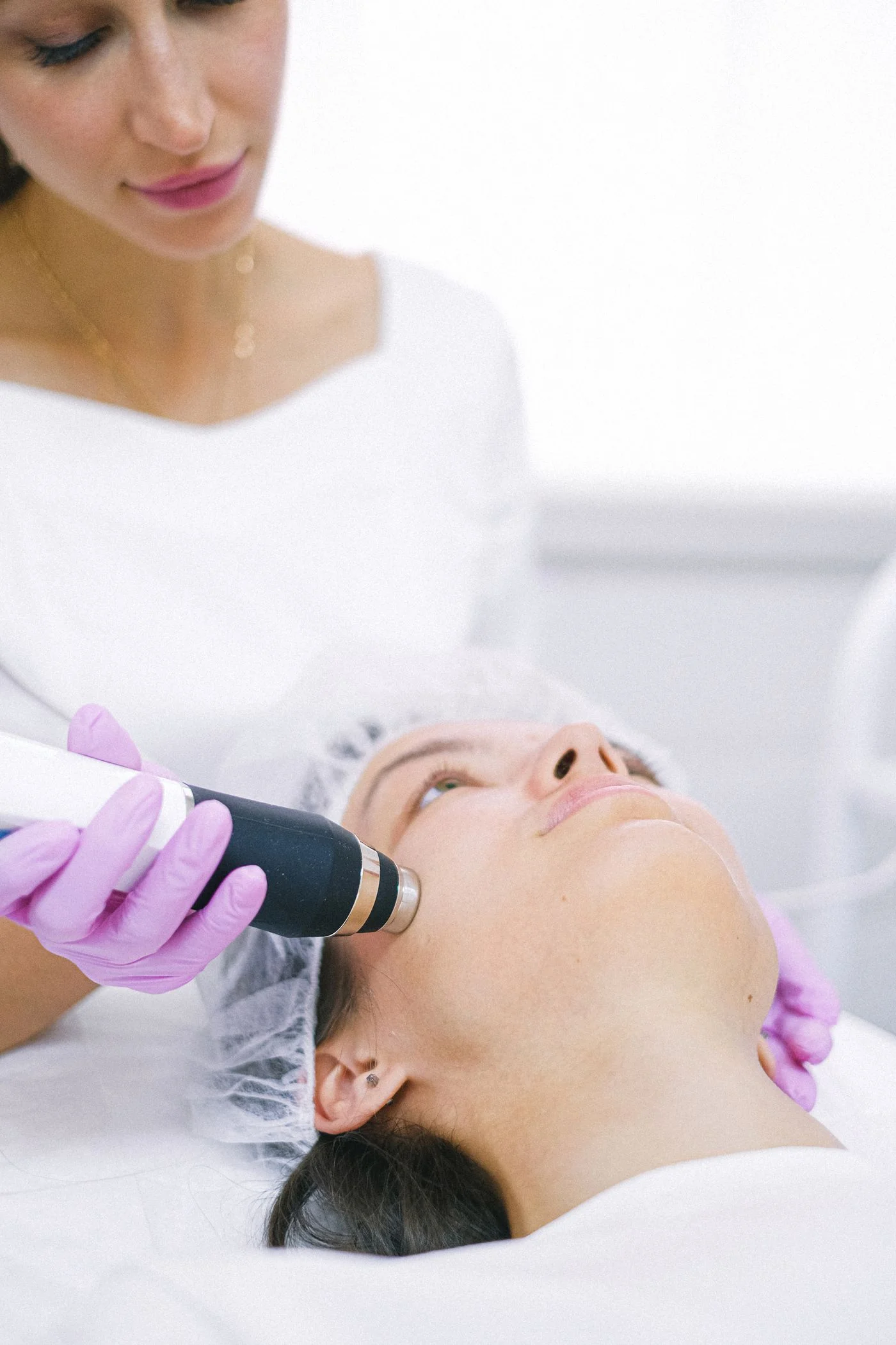 A clinician using an aesthetic handpiece during a facial treatment