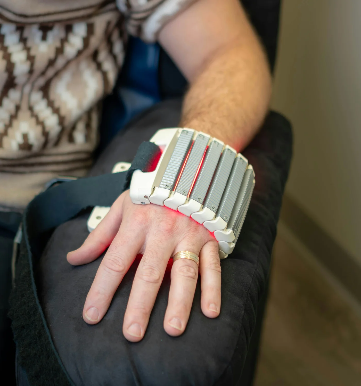 A flexible light-therapy applicator wrapped around a wrist, with red illumination